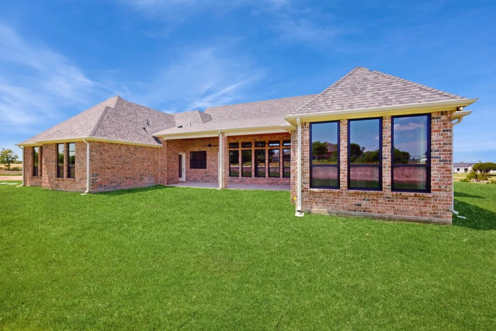 a house wuth a red brick exterior and a gabled, shingled roof and well maintained lawn