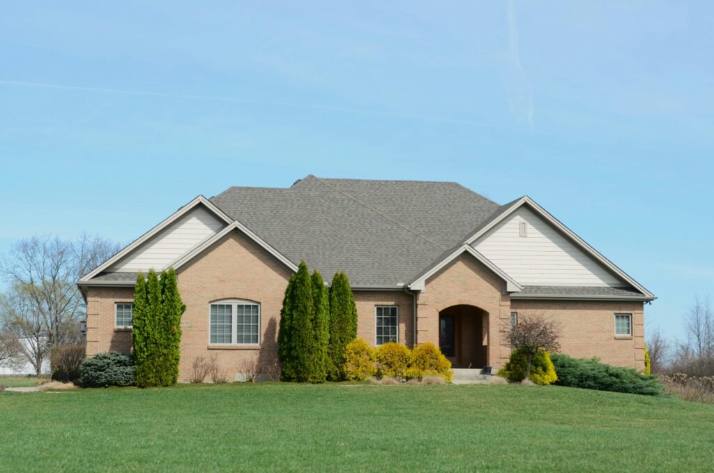 a suburban brick house with a well kept lawn and bushes around the house