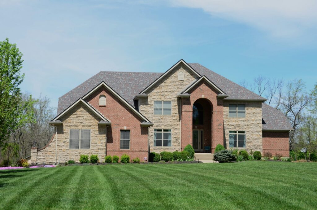 a large brick house with nice grass and small bushes in front of it