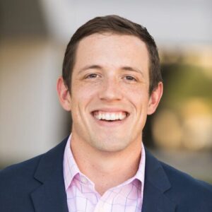Professional headshot of Jared Benson smiling in a dark blazer and light blue shirt